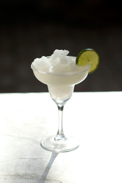 Chilled frozen margarita in a glass garnished with a lime slice.